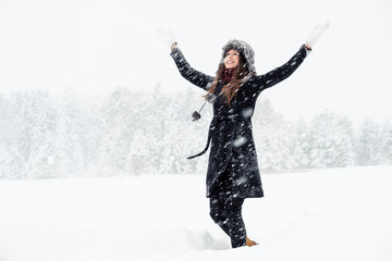 Fototapeta na wymiar Portrait of happy young woman dancing in winter landscape