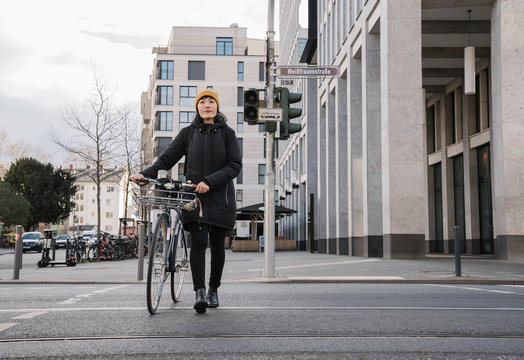 Woman with bicycle in the city on the go, Frankfurt, Germany