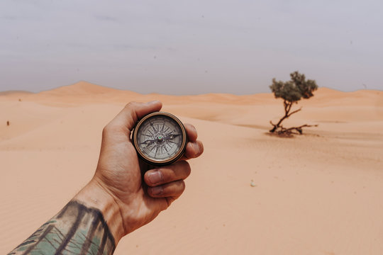 Hand holding compass in the desert
