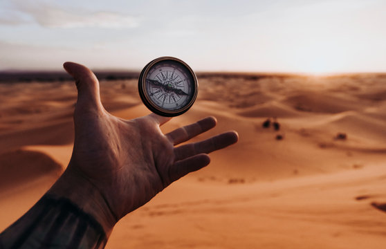 Hand catching compass in the desert