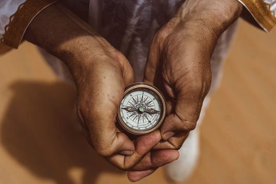 Hands holding compass in the desert, elevated view