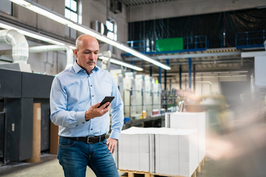 Businessman using cell phone in a factory