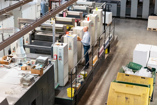 Businessman standing at machines in a printing plant