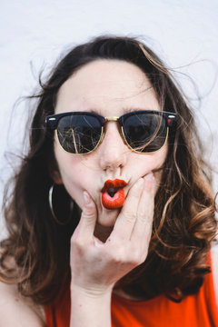 Portrait of young woman with red lips wearing sunglasses pouting mouth
