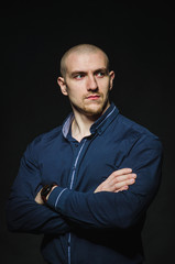 A stylish, bald young man stands on a dark background in the category. Business, Finance