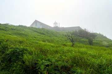 Old lighthouse in the fog on a rock. Gamow Lighthouse on the Gamow Peninsula. Dangerous Bay in the Sea of Japan. Far East.