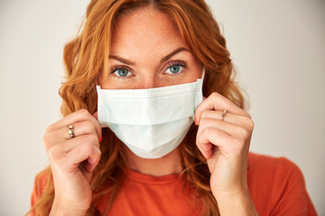 Portrait of red-haired woman wearing a face mask at home