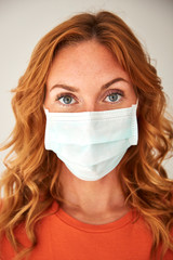 Portrait of red-haired woman wearing a face mask at home