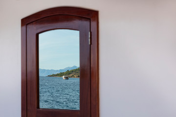Reflection in a window on board of a boat showing the beautiful view over the Dalmatian Adriatic sea with an island in Croatia on a sunny day. The scenery creates the feeling of holiday and freedom