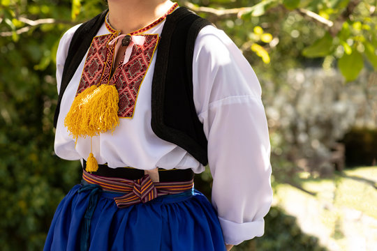 A Detail of a traditional Dalmatian Croatian costume from Cilipi, Dubrovnik. A girl wearing a folklore style outfit with colorful embroidery on a sunny day. Authentic historic clothing from Croatia