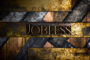 Photo of real authentic typeset letters forming Jobless text on vintage textured grunge copper and black background 