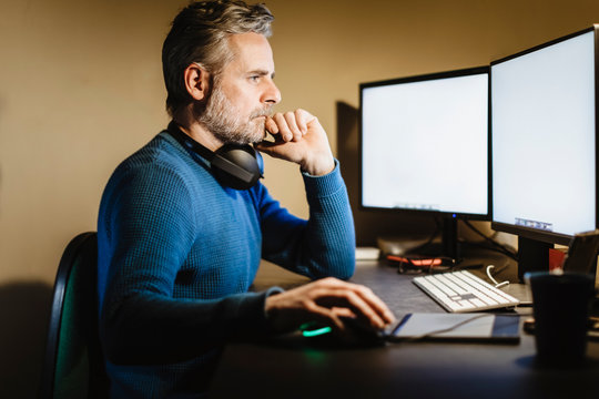 Mature man sitting at desk at home working on computer