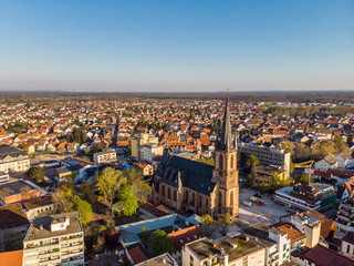 Obraz premium Beautiful morning top view of the central part of Viernheim. Old catholic cathedral. Orange tiled roofs of houses. Germany.