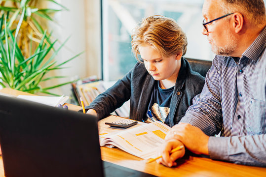 Father helping son doing homework at desk
