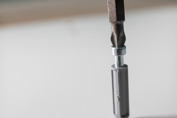 Fototapeta premium Macro shot of self-bearing screw of screwdriver cutting screw with transverse bit into board from furniture cabinet