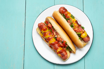 Hot dog with pico de gallo salad on turquoise background