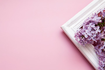 Lilac flowers with a wooden frame on a pink background. Spring concept with mine space.