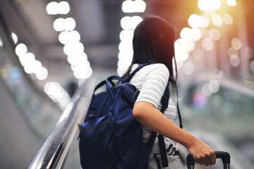 woman tourism hold luggage standing on escalator at airport