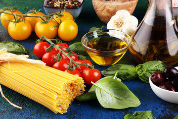 Italian food background with herbs and spices, vine tomatoes, basil, spaghetti, olives, parmesan, olive oil, garlic, peppercorns and fresh rosemary