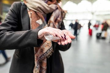 Woman using sanitising hand gel at train station