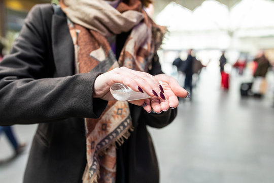 Woman Using Sanitising Hand Gel At Train Station