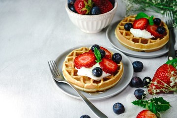 Homemade mini Waffles topped with fresh berries and cream, selective focus
