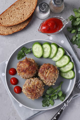 Beef cutlets served with cucumber and tomato sauce on a gray plate on gray concrete background, Vertical format