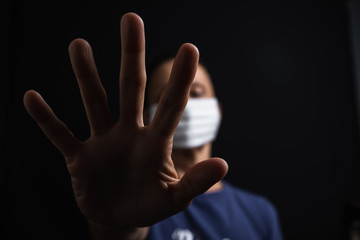 Elderly person wearing a mask to prevent the spread of the coronavirus during the pandemic, making an stop sign.