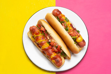 Hot dog with pico de gallo salad on pink and yellow background