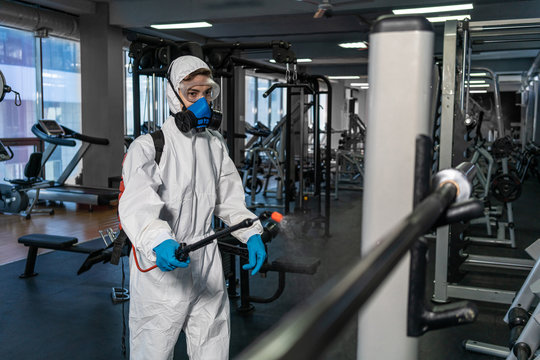 Cleaning and Disinfection in crowded places amid the coronavirus epidemic Gym cleaning and disinfection Infection prevention and control of epidemic. Protective suit and mask and spray bag COVID-19