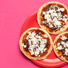 Mexican red sopes with cheese and beans on pink background