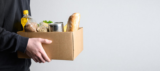 Volunteer holding donation food with goods. Banner. Delivery food. Copy space.