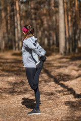 Fototapeta premium Girl does warm-up before exercising. Running in the pine forest.