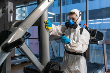 Cleaning and Disinfection in crowded places amid the coronavirus epidemic Gym cleaning and disinfection Infection prevention and control of epidemic. Protective suit and mask and spray bag COVID-19