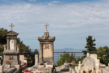 Fototapeta na wymiar Old traditional graveyard, cemetery near the famous mausoleum in Cavtat, small town near Dubrovnik, Dalmatia Croatia. Graves are placed on a hill with view to the sea, mountains, and an island