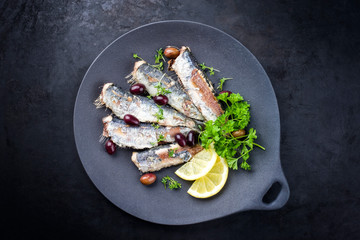 Fried sardines with lettuce and kalamata olives offered as top view on a modern design plate with...