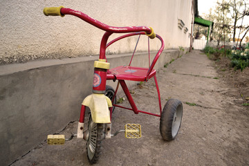 old tricycle in the yard under the wall