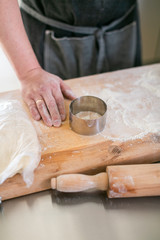 Crop chef working with dough. Faceless man at steel table with wooden board