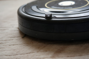 close-up of an robotic vacuum cleaner on carpet smart cleaning technology. Used old robotic vacuum cleaner.