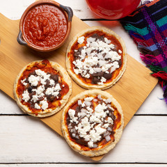 Mexican red sopes with cheese and beans on white background