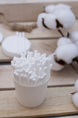 Clean cotton sticks for personal ears hygiene. Cotton buds and discs on wooden tray with cotton branch.