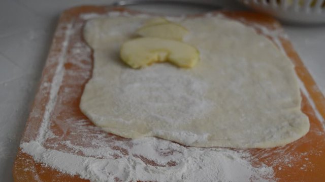 Rolled wheat dough  with apples and rolling pin on a table 