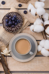 Yammy! Cup of coffee on wooden serving tray and donut with blueberry, morning concept, cotton flower top view