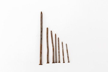rusty nails are laid out in order from large to small on a white background