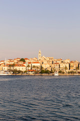 Fototapeta na wymiar Korcula island with the old city walls, view from the sea on a sunny day during sunset. Clear adriactic sea, the mediterranean coast of Croatia, Europe. Seascape creating an idyllic scenery