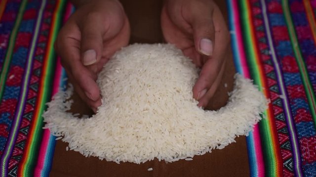 
hand lifting rice with colorful blanket