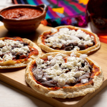 Mexican red sopes with cheese and beans on white background