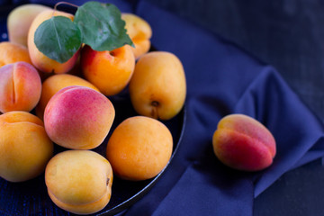 Fresh apricot on dark silk fabric. Ripe sweet berries in droplets of water