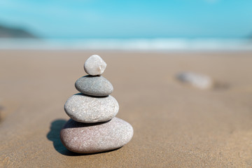 Fototapeta na wymiar Pyramid of stones for meditation lying on sea coast. Five white stones tower. Simple poise stones. Simplicity harmony and balance, rock zen sculptures. Zen and relax concept.