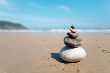 Pyramid of stones for meditation lying on sea coast. Five colored stones tower. Simple poise stones. Simplicity harmony and balance, rock zen sculptures. Zen and relax concept.